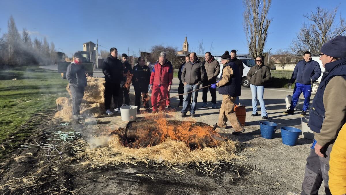 Personas alrededor de fuego y paja en la fiesta de la matanza de Rágama